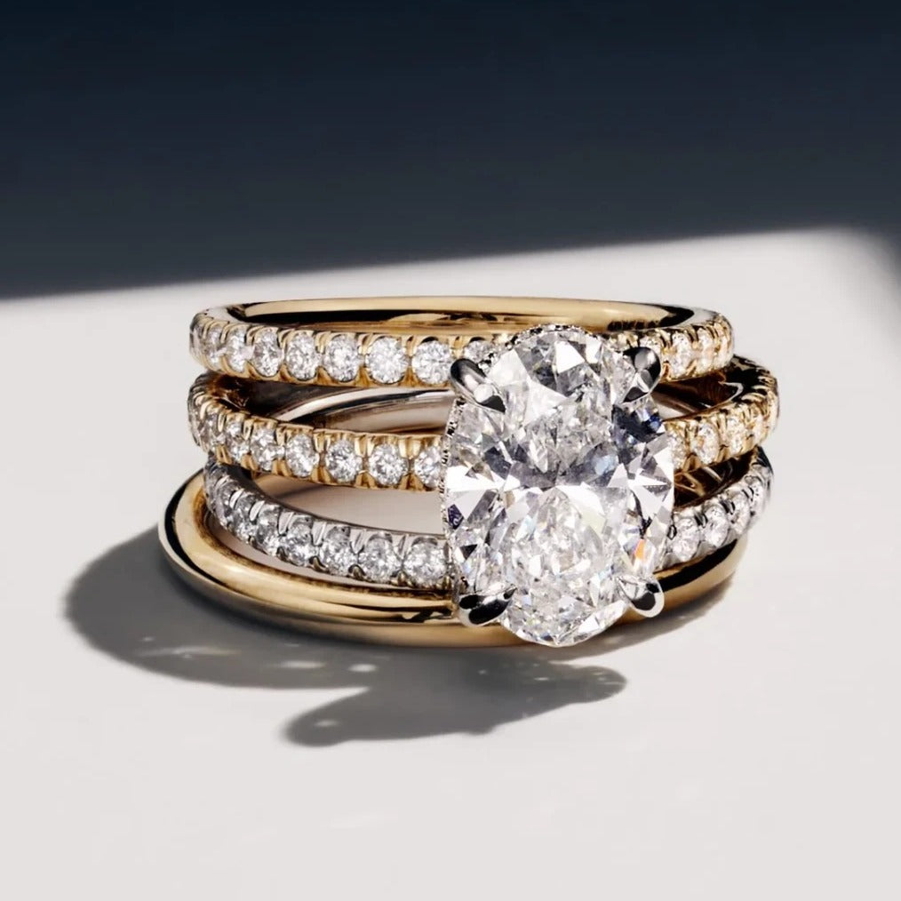 Oval lab diamond engagement ring stacked with gold and platinum eternity bands